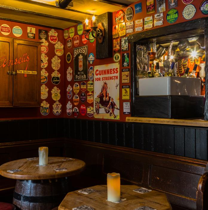 interior of old public house with walls decorated with beer mats and barrel tables.