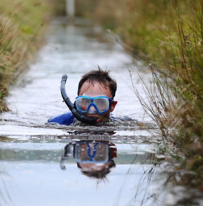 Image of a person wearing a snorkel and mask in a bog.