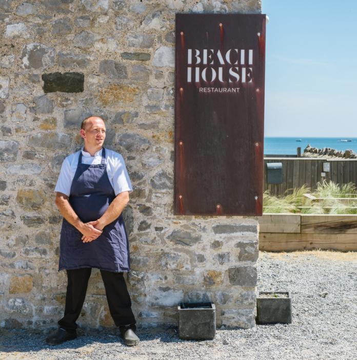 Hywel Griffiths chef standing by his Beach House restaurant sign.