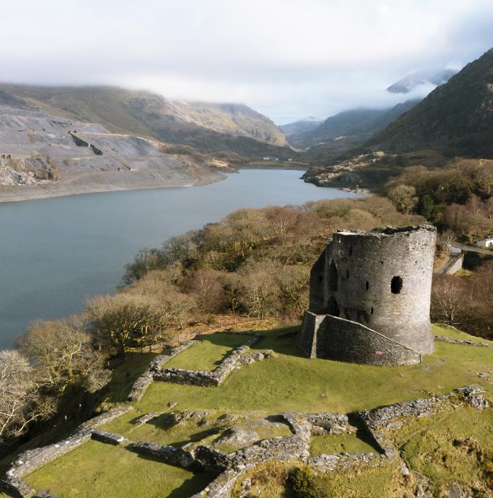 A ruined castle overlooking a large lake. 