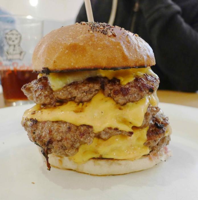 A massive bacon and cheese burger on a table.