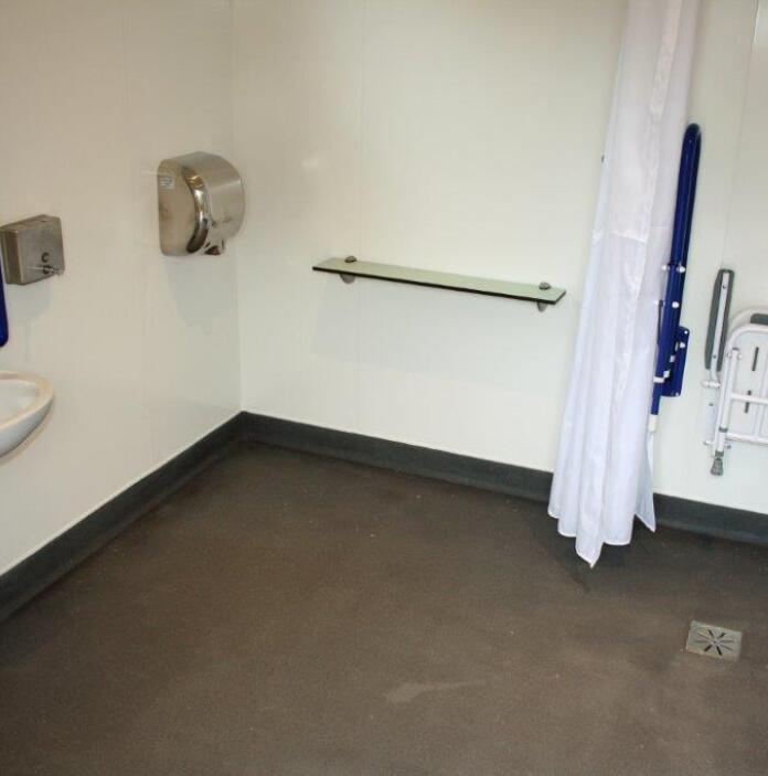 Accessible wet room with grab rails and a fold-down seat.