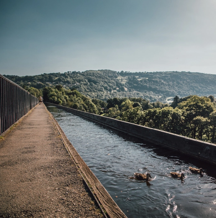 An aqueduct made of a metal trough and a narrow footpath. 