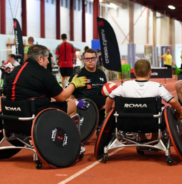 A team of wheelchair rugby players in a sports hall.