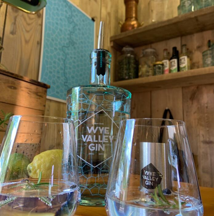 A bottle of Wye Valley Gin made at Silver Circle Distillery and two glasses with gin, rosemary and blueberries in them.