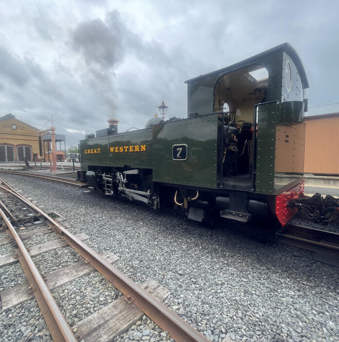 A dark green narrow gauge steam locomotive at the front of a train.