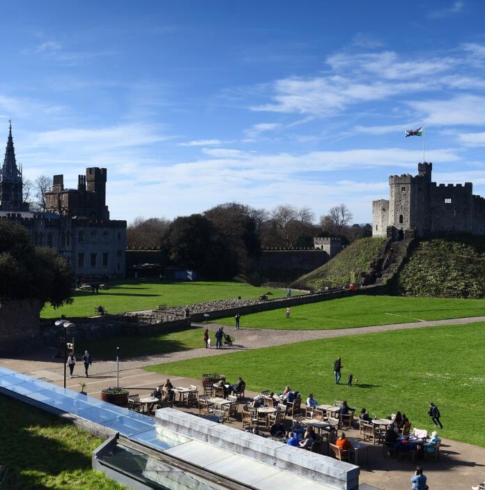 outdoor seating and people with castle buildings in background.