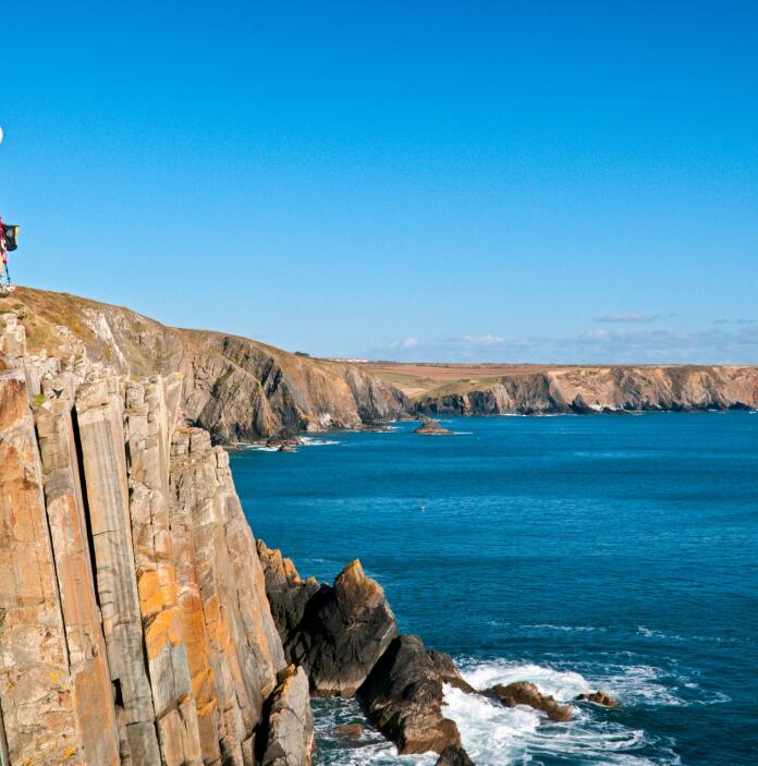 climber climbing coastal cliff.