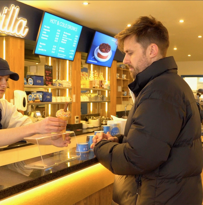 A man buying an ice cream inside an ice cream parlour.