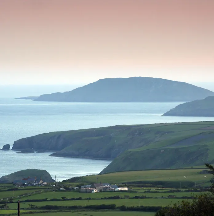 A picturesque view of Bardsey Island, featuring its rugged coastline and lush greenery.