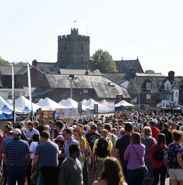 Crowds of people on a street enjoying a food stall filled food festival.