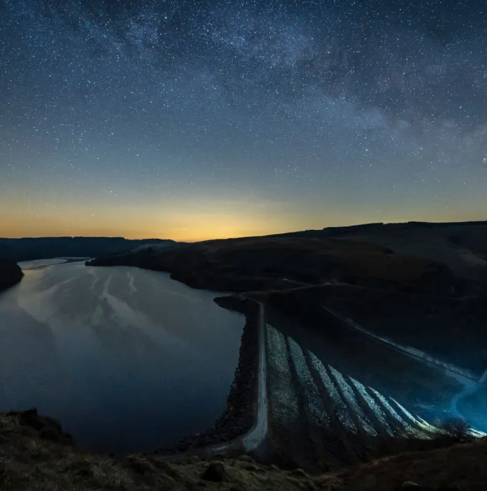 Dark skies above a remote reservoir and dam.