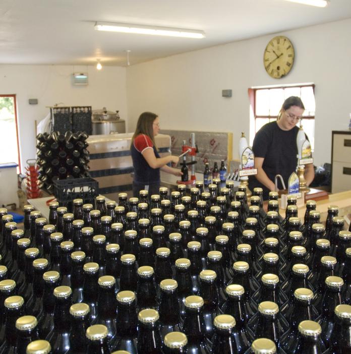 Two ladies working  at Gwaun Valley Brewery with hundreds of bottles of beer in the foreground.