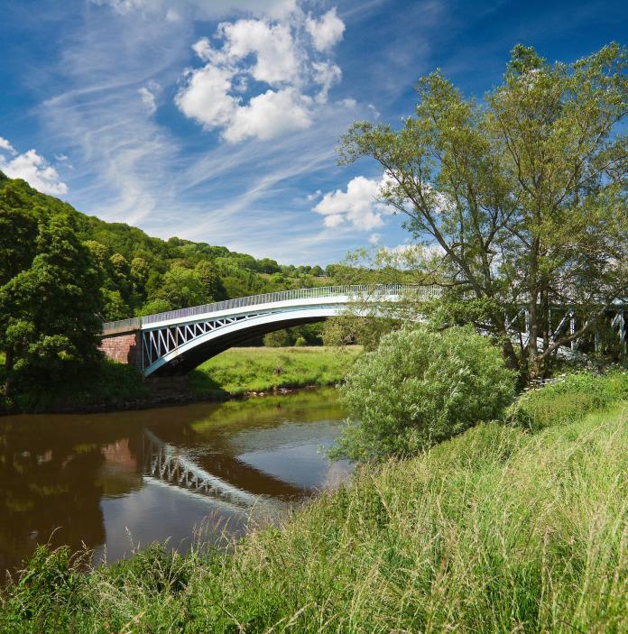 Bigsweir Bridge spanning the River Wye with grass and trees on the river banks.