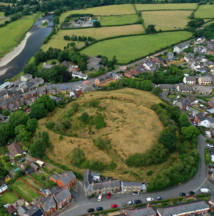 Aerial view of grassy mound surrounded by a town.