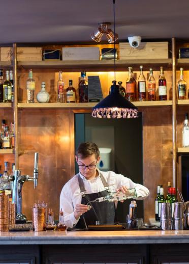Ein Barkeeper schenkt einen Cocktail hinter einer Bar in einem gehobenen Restaurant in Cardiff ein.