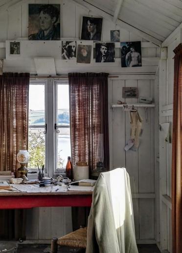 In Dylan Thomas' Bootshaus, Schreibtisch, Stuhl und Bildern an der Wand.