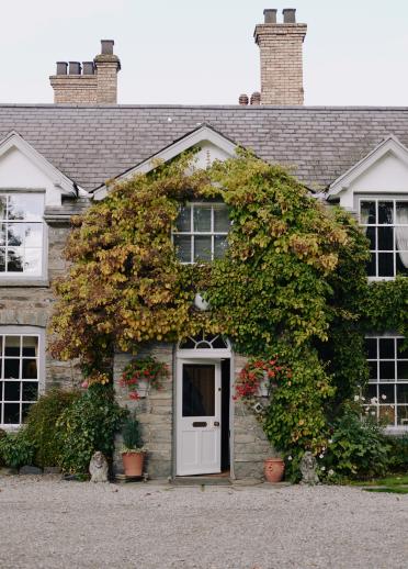 The front of a cottage style restaurant covered in ivy.