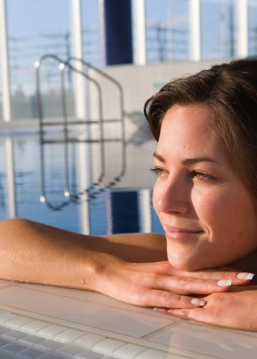 A woman resting on the edge of a quiet spa pool.