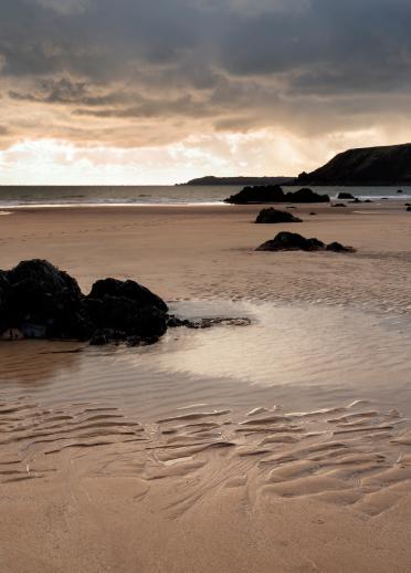 Beach at Marloes Sands with dark clouds.