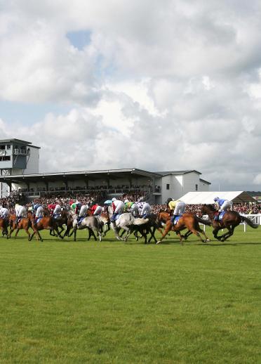 Jockeys riding their horses on the race track at Ffos Las Racecourse.
