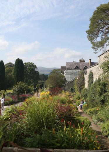 Walled gardens with flowers and plants and people walking at Bodnant Garden.