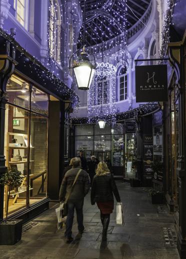 people walking through Victorian shopping arcade decorated with Christmas lights.