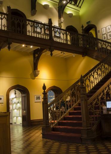 Großes Treppenhaus und Flur der Kunstgalerie Plas Glyn-y-Weddw mit Kunstwerken an den Wänden.