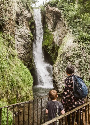 A small boy and a woman looking at Dyserth Waterfall.