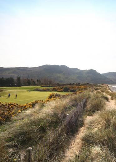 Golfers playing at Conwy golf course by the sea. 