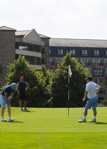 Group of golfers on the green with Celtic Manor Resort in the backgroud.