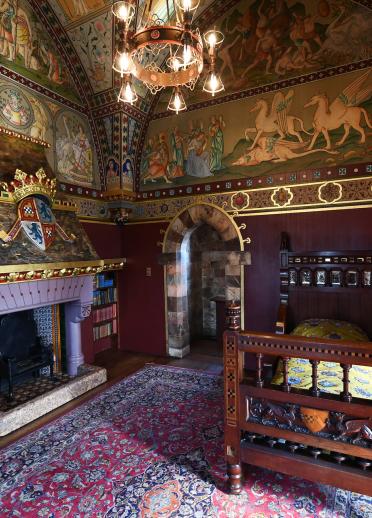 Prunkvolles viktorianisches Schlafzimmer mit Bett, dekorativem Kamin und Kronleuchter.