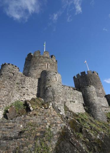 Looking directly up to the ihe imposing Conwy Castle in blue sky.