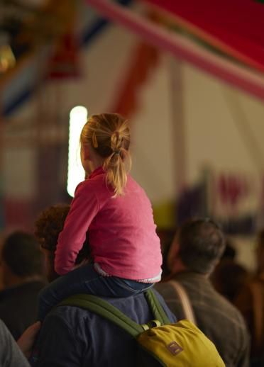 A crowd watching a musician on stage in a tent.
