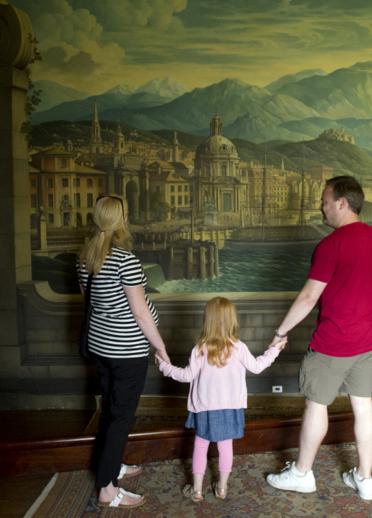 Besucher betrachten das Wandgemälde von Rex Whistler im Speisesaal des Herrenhauses Plas Newydd, Anglesey, Wales.