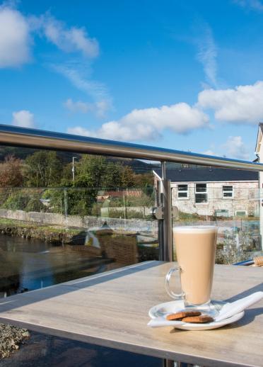 Kaffee auf einem Tisch im Freien mit Blick über einen Fluss.