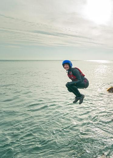 Image os woman jumping in the sea, coasteering near St David's