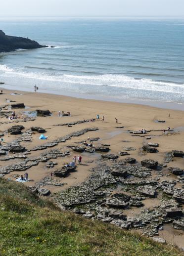 A busy sandy beach with rockpools and cliffs.
