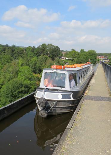 Ein Schmalspurboot, das an einem sonnigen Tag auf einem Aquädukt fährt.
