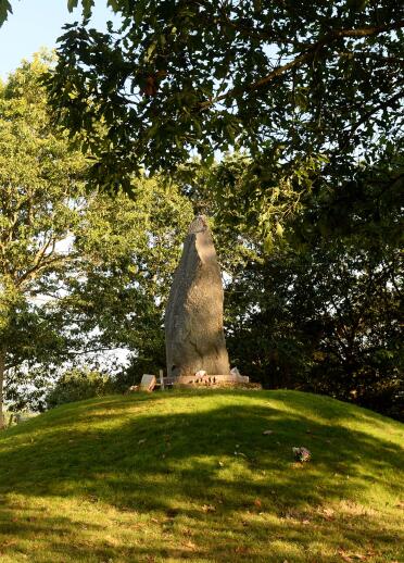Monolith on grassy mound.