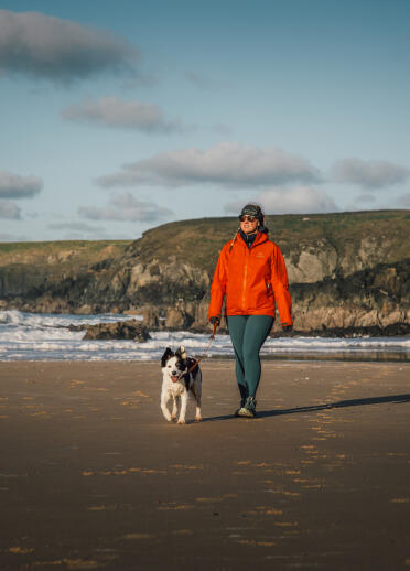 woman walking dog on beach.