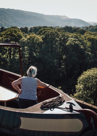 woman on boat on aqueduct, with views of water and countryside.