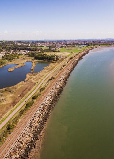 An aerial view of a coastal cycle trail passing a lake. 