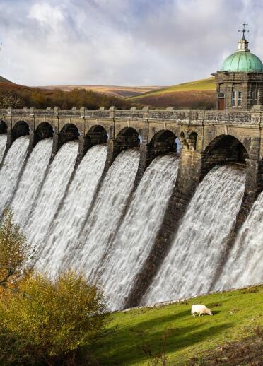 An ornate stone dam spilling over with water.