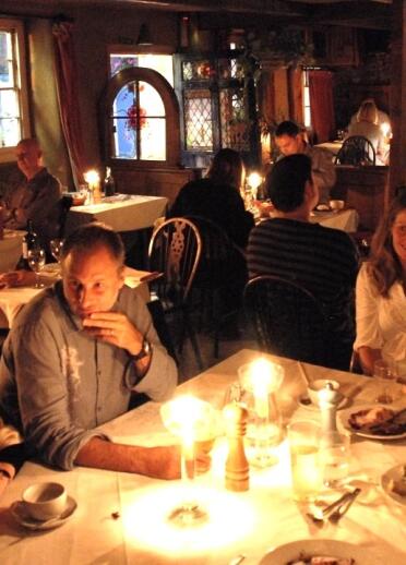 groups of people eating at tables by candlelight.
