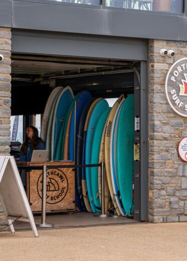 Outside of a surf school building / shop, with surfboards on view.