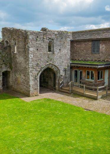 The courtyard of a large fifteen century stone house and tower with an arched doorway.