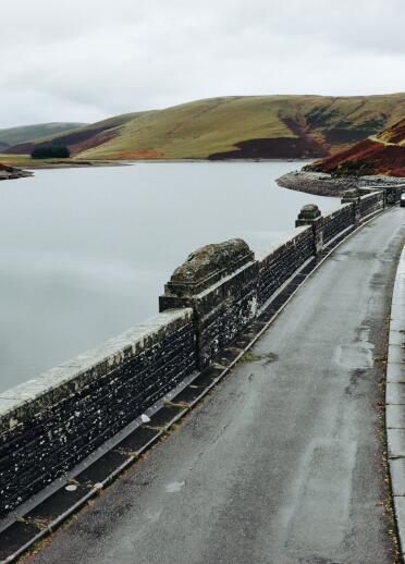 car driving on stone bridge with reservoir.