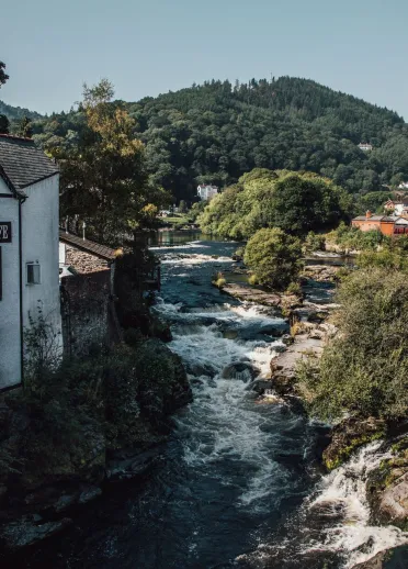 A river flowing through the town next to a white building.