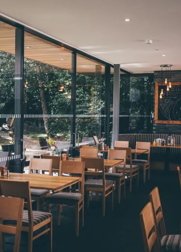 Interior of restaurant with chairs and tables and large glass window.